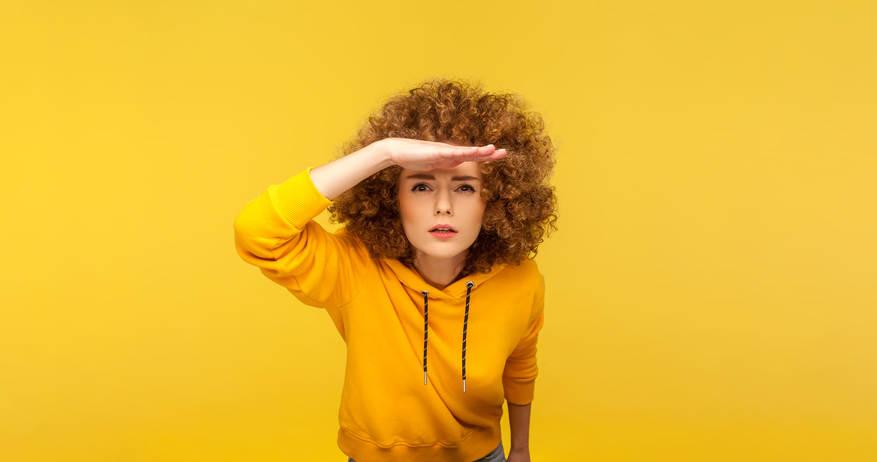 Woman against yellow background searching for something